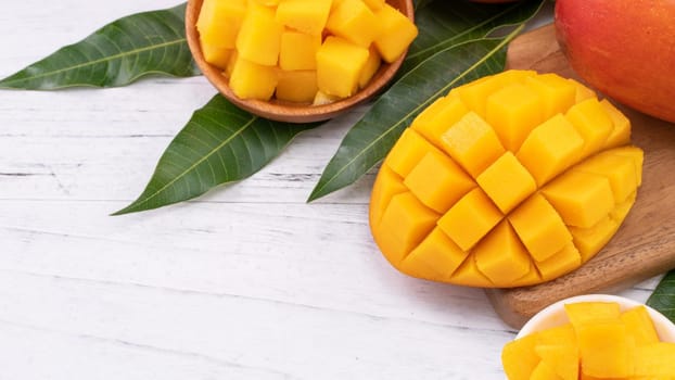 Fresh chopped mango on a tray and bright rustic wooden background. Tropical summer fruit design concept, close up, macro, copy space.
