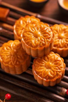Chinese traditional pastry Moon cake Mooncake with tea cups on bamboo servingwarning tray on wooden background for Mid-Autumn Festival, close up.