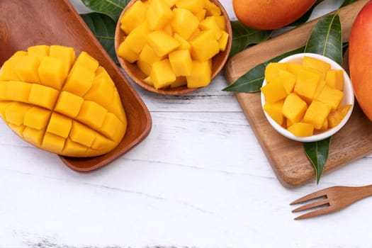 Fresh chopped mango on a tray and bright rustic wooden background. Tropical summer fruit design concept, close up, macro, copy space.
