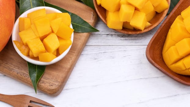 Fresh chopped mango on a tray and bright rustic wooden background. Tropical summer fruit design concept, close up, macro, copy space.