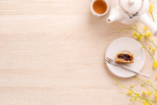 Tasty moon cake for Mid-Autumn festival on bright wooden table, concept of festive afternoon tea decorated with yellow flowers, top view, flat lay.