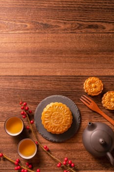 Chinese traditional pastry Moon cake Mooncake with tea cups on bamboo serving tray on wooden background for Mid-Autumn Festival, top view, flat lay.