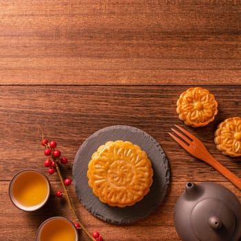 Chinese traditional pastry Moon cake Mooncake with tea cups on bamboo serving tray on wooden background for Mid-Autumn Festival, top view, flat lay.