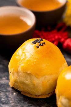 Tasty baked egg yolk pastry moon cake for Mid-Autumn Festival on black slate dark background. Chinese festive food concept, close up, copy space.