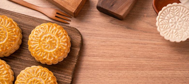 Round shaped fresh baked moon cake pastry - Chinese moonckae for Mid-Autumn Moon Festival on wooden background and serving tray, top view, flat lay.