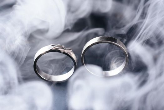 Two golden wedding rings with white smoke around