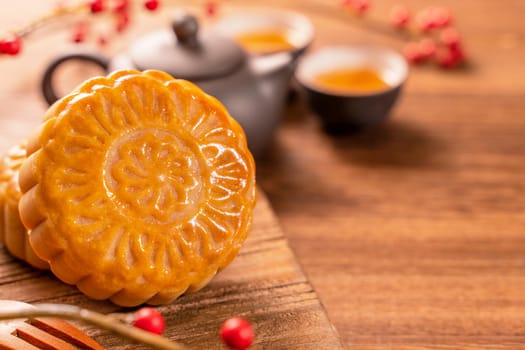 Chinese traditional pastry Moon cake Mooncake with tea cups on bamboo serving tray on wooden background for Mid-Autumn Festival, close up.