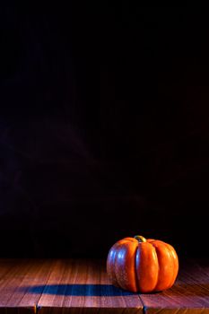 Halloween concept - Orange pumpkin lantern on a dark wooden table with black background, trick or treat, close up.