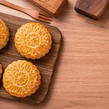 Round shaped fresh baked moon cake pastry - Chinese moonckae for Mid-Autumn Moon Festival on wooden background and serving tray, top view, flat lay.