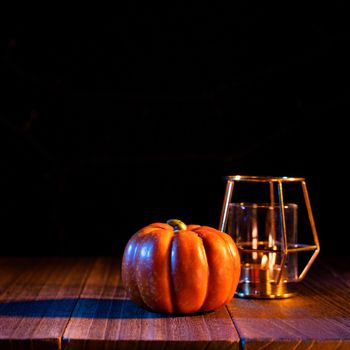 Halloween concept - Orange pumpkin lantern on a dark wooden table with black background, trick or treat, close up.