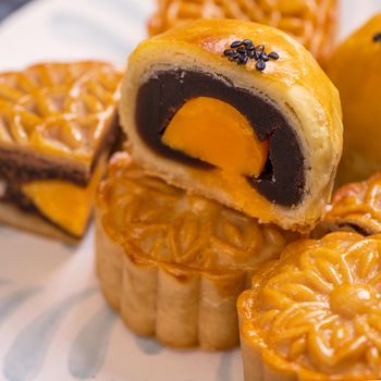 Tasty baked egg yolk pastry moon cake for Mid-Autumn Festival on black slate dark background. Chinese festive food concept, close up, copy space.