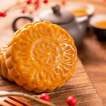 Chinese traditional pastry Moon cake Mooncake with tea cups on bamboo serving tray on wooden background for Mid-Autumn Festival, close up.