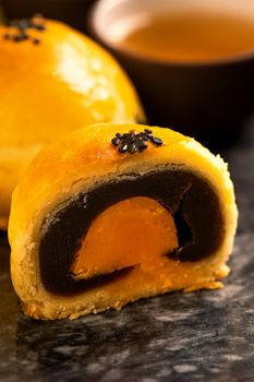 Tasty baked egg yolk pastry moon cake for Mid-Autumn Festival on black slate dark background. Chinese festive food concept, close up, copy space.