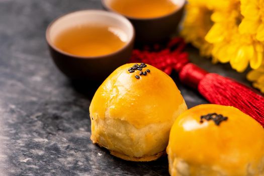 Tasty baked egg yolk pastry moon cake for Mid-Autumn Festival on black slate dark background. Chinese festive food concept, close up, copy space.