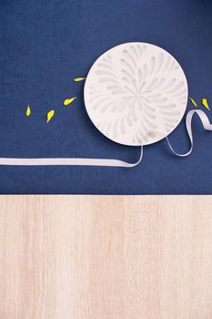 Conceptual Mid-Autumn Festival table background, symbol of moon, clouds and stars in the sky with plate, ribbon and yellow petal. Top view, flat lay.