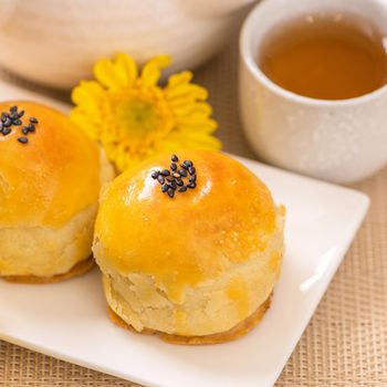 Tasty baked egg yolk pastry moon cake for Mid-Autumn Festival on bright wooden table background. Chinese festive food concept, close up, copy space.