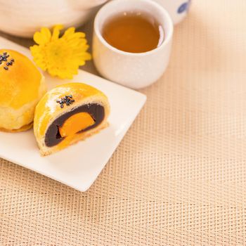 Tasty baked egg yolk pastry moon cake for Mid-Autumn Festival on bright wooden table background. Chinese festive food concept, close up, copy space.