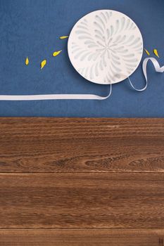 Conceptual Mid-Autumn Festival table background, symbol of moon, clouds and stars in the sky with plate, ribbon and yellow petal. Top view, flat lay.