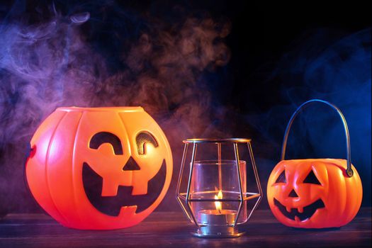 Halloween concept - Orange pumpkin lantern on a dark wooden table with double colored smoke around the background, trick or treat, close up.
