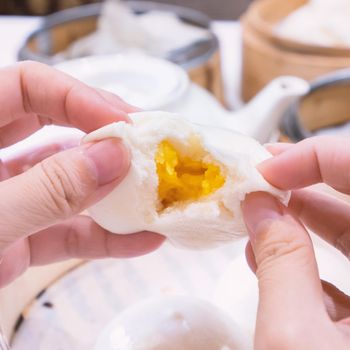 Delicious dim sum, famous cantonese food in asia, fresh and hot salted creamy custard buns in bamboo steamer in hong kong yumcha restaurant, close up