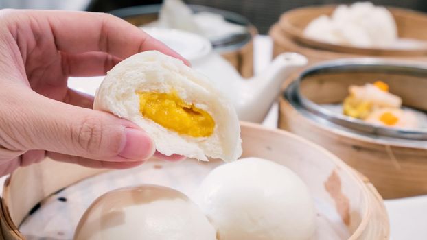 Delicious dim sum, famous cantonese food in asia, fresh and hot salted creamy custard buns in bamboo steamer in hong kong yumcha restaurant, close up