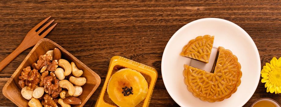 Moon cakes with tea on dark wooden table, holiday concept of Mid-Autumn festival traditional food layout design, top view, flat lay, copy space.