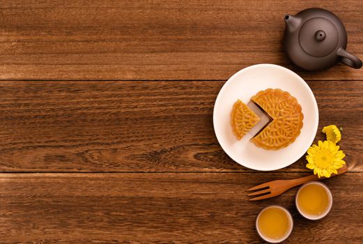 Moon cakes with tea on dark wooden table, holiday concept of Mid-Autumn festival traditional food layout design, top view, flat lay, copy space.