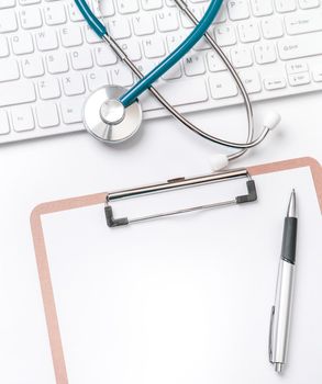 Doctor diagnoses concept - stethoscope on computer keyboard with medical record case and pen on white working table. Top view, flat lay, copy space