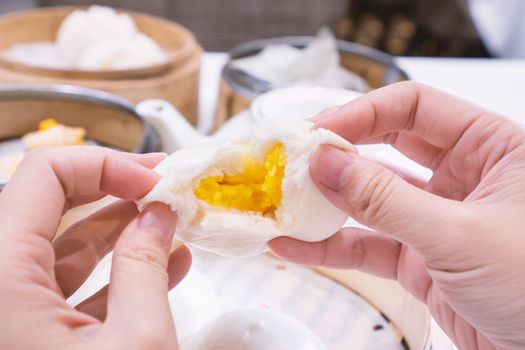 Delicious dim sum, famous cantonese food in asia, fresh and hot salted creamy custard buns in bamboo steamer in hong kong yumcha restaurant, close up
