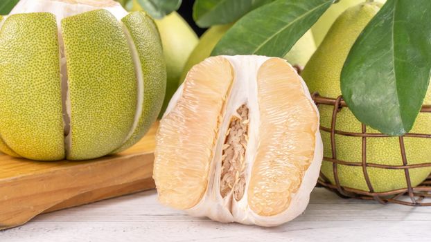 Fresh peeled pomelo, grapefruit, shaddock with green leaf on bright wooden plank table. Seasonal fruit near mid-autumn festival, close up, copy space