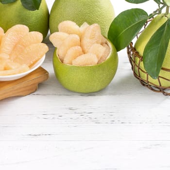 Fresh peeled pomelo, grapefruit, shaddock with green leaf on bright wooden plank table. Seasonal fruit near mid-autumn festival, close up, copy space