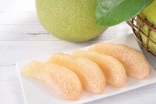 Fresh peeled pomelo, grapefruit, shaddock with green leaf on bright wooden plank table. Seasonal fruit near mid-autumn festival, close up, copy space