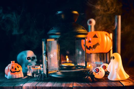 Halloween concept, spooky decorations with lighting up candle and candle holder with green tone smoke around on a dark wooden table, close up.