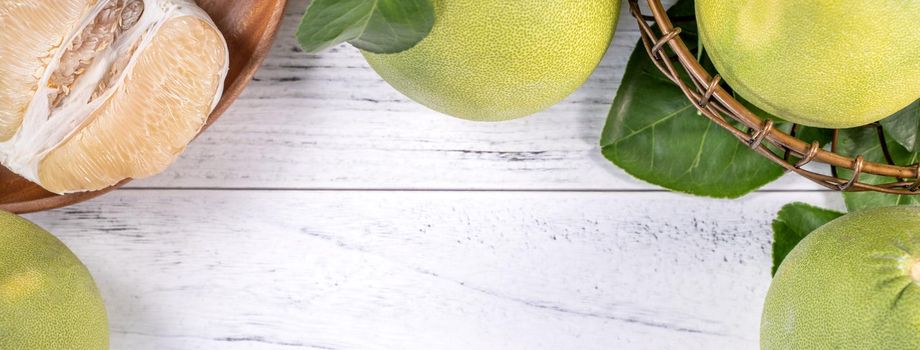 Fresh peeled pomelo, grapefruit, shaddock with green leaf on bright wooden plank table. Seasonal fruit near mid-autumn festival, top view, copy space