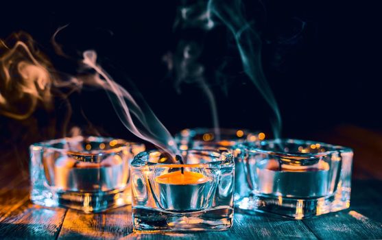 Halloween concept, spooky decorations with lighting up candle and candle holder with green tone smoke around on a dark wooden table, close up.