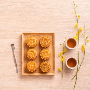 Moon cakes with tea on bright wooden table, holiday concept of Mid-Autumn festival traditional food layout design, top view, flat lay, copy space.
