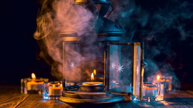 Halloween concept, spooky decorations with lighting up candle and candle holder with green tone smoke around on a dark wooden table, close up.