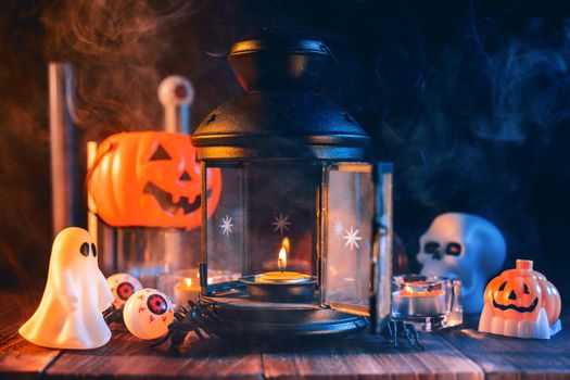 Halloween concept, spooky decorations with lighting up candle and candle holder with blue tone smoke around on a dark wooden table, close up.