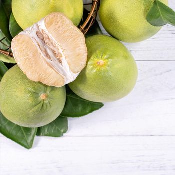 Fresh peeled pomelo, grapefruit, shaddock with green leaf on bright wooden plank table. Seasonal fruit near mid-autumn festival, top view, copy space