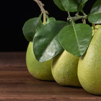 Fresh peeled pomelo, grapefruit, shaddock with green leaves on dark wooden plank table. Seasonal fruit near mid-autumn festival, close up, copy space