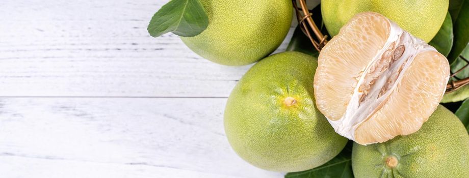 Fresh peeled pomelo, grapefruit, shaddock with green leaf on bright wooden plank table. Seasonal fruit near mid-autumn festival, top view, copy space