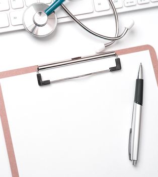 Doctor diagnoses concept - stethoscope on computer keyboard with medical record case and pen on white working table. Top view, flat lay, copy space
