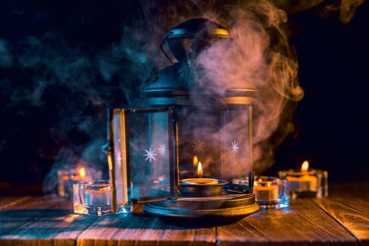 Halloween concept, spooky decorations with lighting up candle and candle holder with green tone smoke around on a dark wooden table, close up.