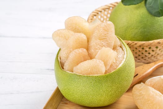 Fresh peeled pomelo, grapefruit, shaddock with green leaf on bright wooden plank table. Seasonal fruit near mid-autumn festival, close up, copy space
