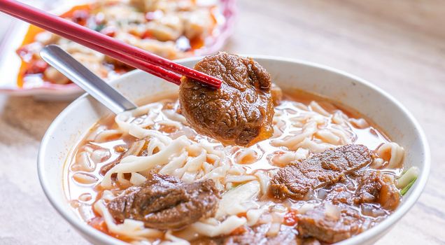 Beef noodle - Taiwan ramen meal with tomato sauce broth in bowl on bright wooden table, famous chinese style food, close up, top view, copy space