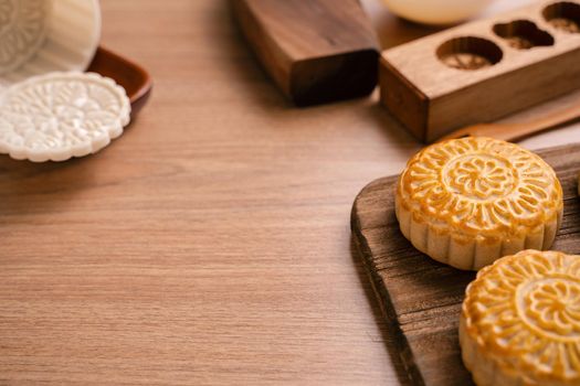 Round shaped moon cake Mooncake - Chinese style traditional pastry during Mid-Autumn Festival / Moon Festival on wooden background and tray, close up