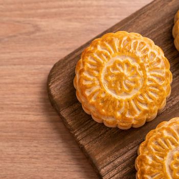 Round shaped moon cake Mooncake - Chinese style pastry during Mid-Autumn Festival / Moon Festival on wooden background and tray, top view, flat lay.