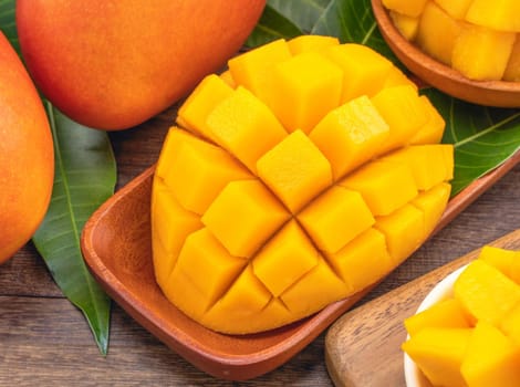 Fresh chopped mango cubes on wooden cutting board and rustic timber background. Tropical summer fruit concept, close up, macro, copy space.