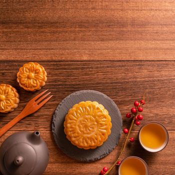 Moon cake Mooncake table setting - Chinese traditional pastry with tea cups on wooden background, Mid-Autumn Festival concept, top view, flat lay.
