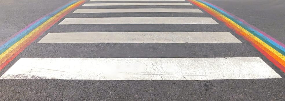 Marked crosswalk with lbgtq pride flag rainbow stripes. Colored chalk